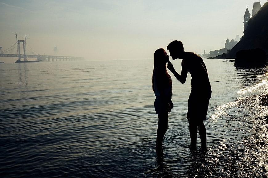 Silhouette of couple kissing on beach at sunset