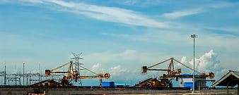 Yellow industrial cranes at construction site under blue sky