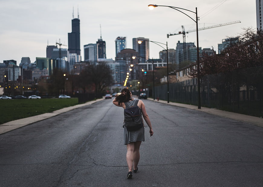 Woman Walking Down City Street with Skyline Background