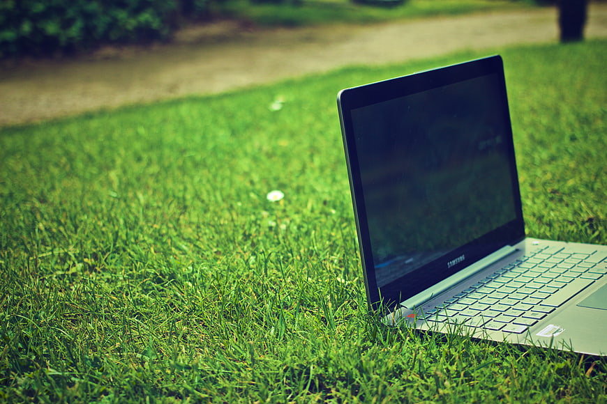 Open Laptop Computer Resting On Green Grass In Park