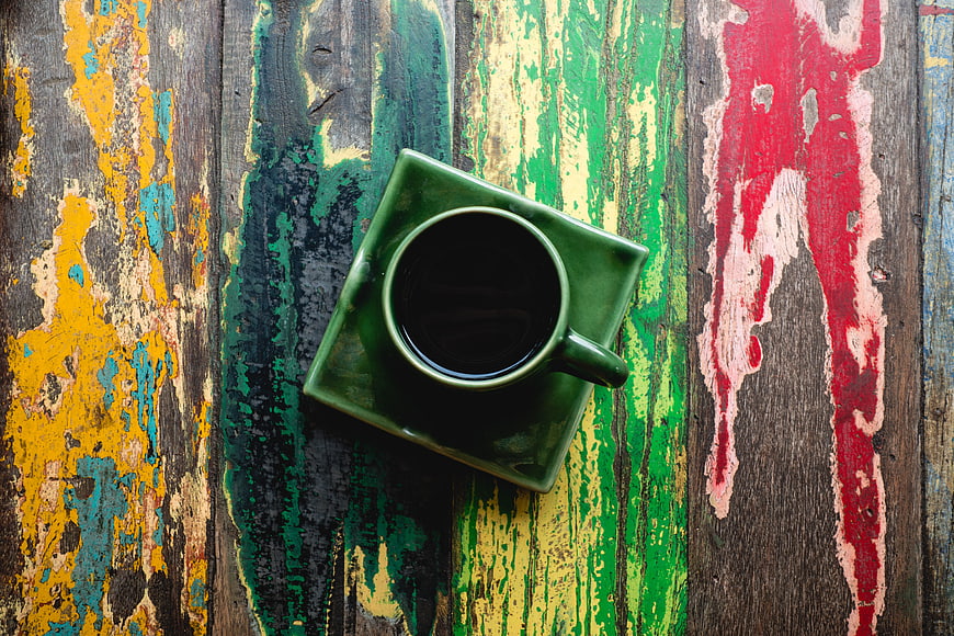 Top View of Green Coffee Cup on Colorful Distressed Wood
