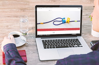 Person browsing coaching website on laptop with coffee