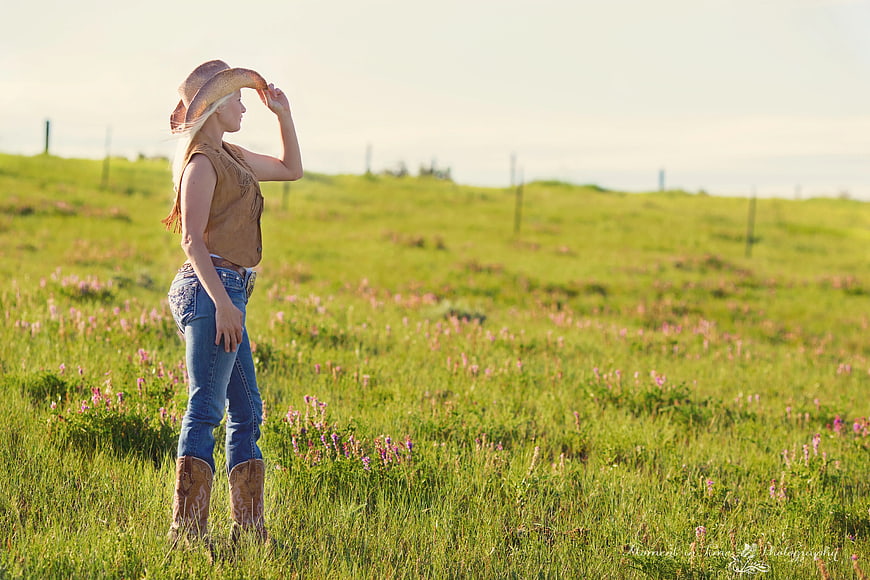 Woman in Cowboy Hat and Boots Standing in Green Meadow