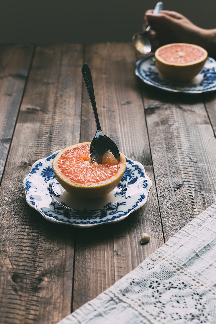 Halved grapefruit on vintage blue and white plate with spoon
