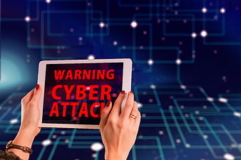 Hands holding tablet with cyber attack warning screen