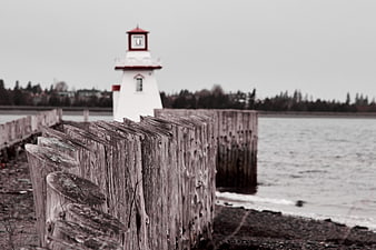 Weathered Wooden Seawall with Blurred Lighthouse Background