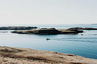 Small boat navigating calm blue waters near rocky coastal islands