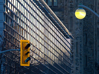 Yellow Traffic Light Against Modern Glass Building Facade