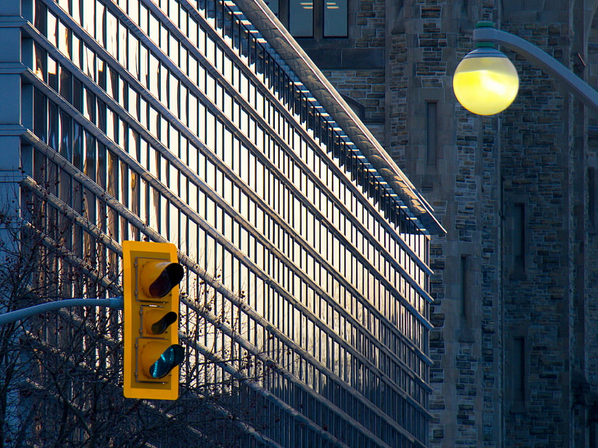 Yellow Traffic Light Against Modern Glass Building Facade