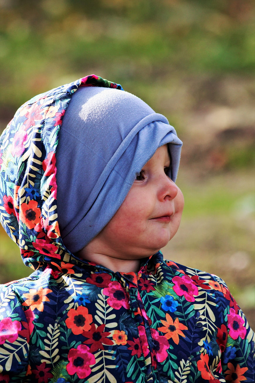 Close-up portrait of a smiling toddler in a floral hooded jacket