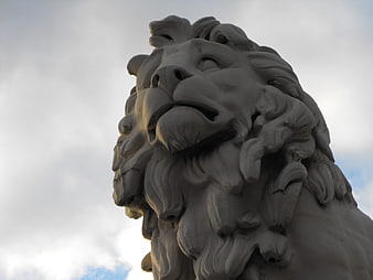 Low angle view of stone lion statue head against cloudy sky