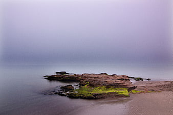 Misty Coastal Rocks with Green Moss and Smooth Ocean Water