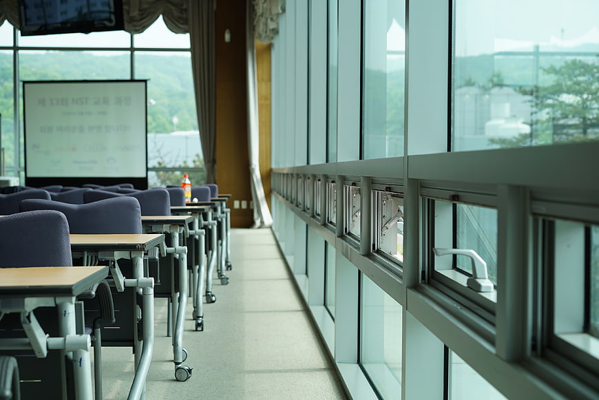 Empty modern lecture hall with rows of desks and large windows