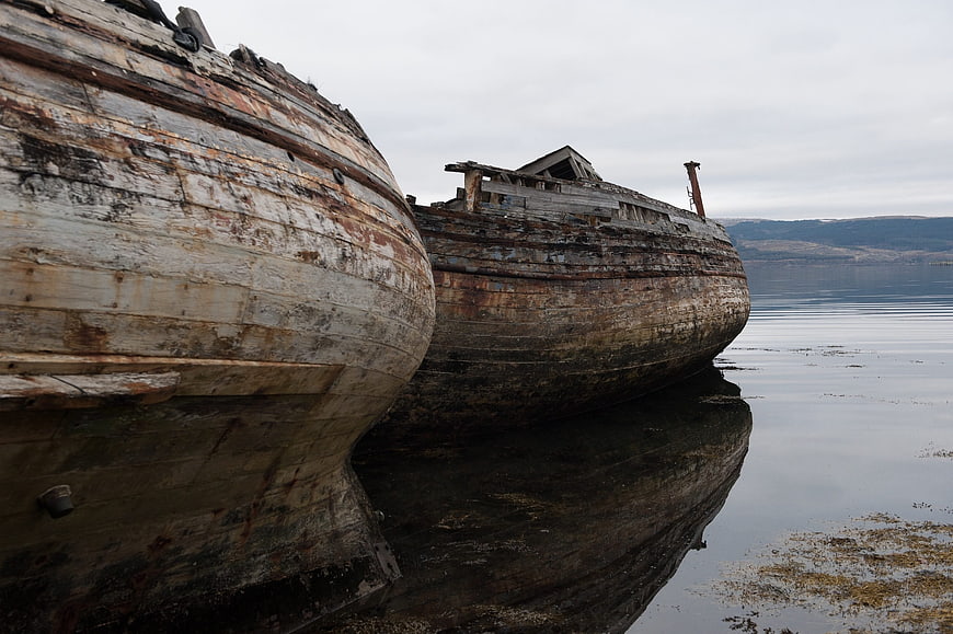 Weathered wooden boat hulls resting on calm water