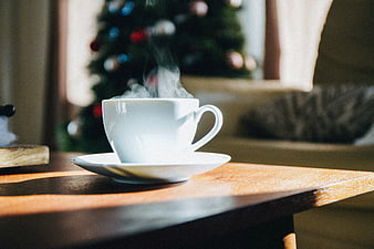Steaming White Coffee Cup on Wooden Table with Christmas Tree