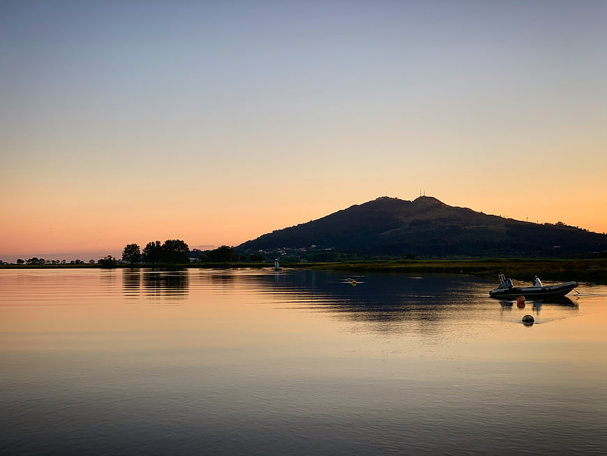 Serene Lake Sunset with Mountain Silhouette and Moored Boat