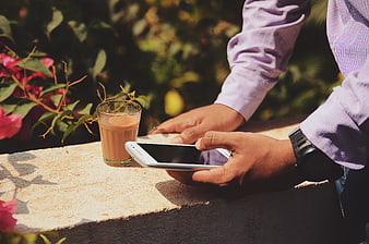 Man using smartphone with iced coffee outdoors