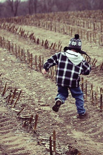 Child running through harvested cornfield in winter