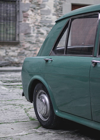 Vintage Green Car Parked on Cobblestone Street
