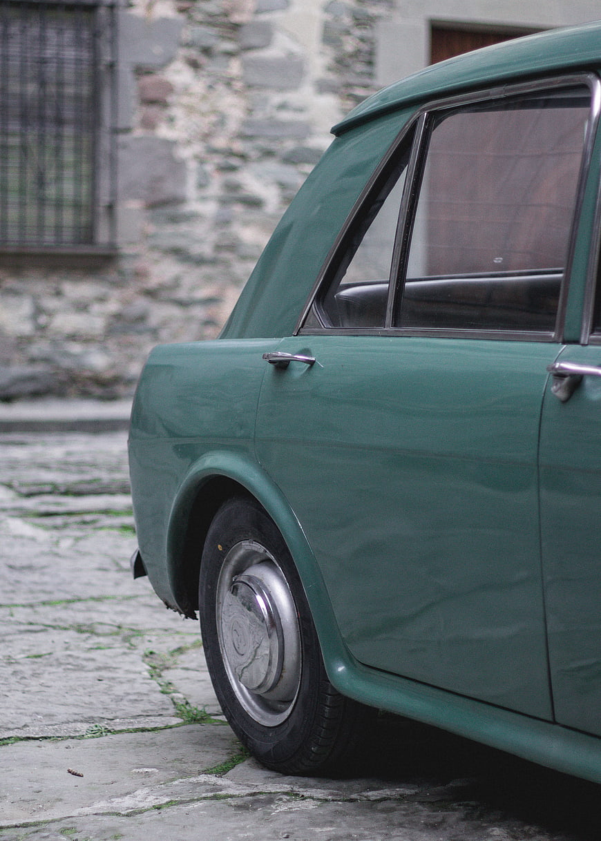 Vintage Green Car Parked on Cobblestone Street