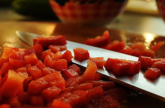 Close-up of diced red peppers on a knife blade