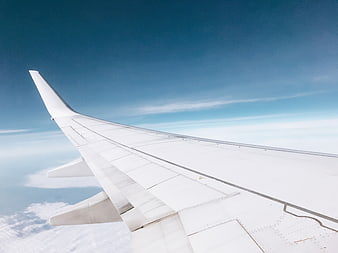 Airplane wing view above clouds in blue sky