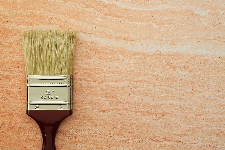 Paintbrush on textured peach background with copyspace