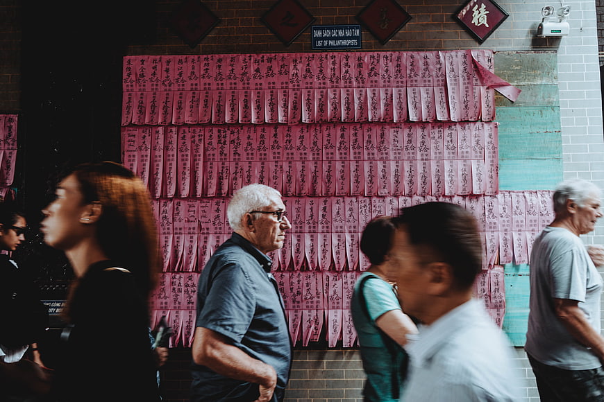 Tourists viewing red prayer slips at a temple wall