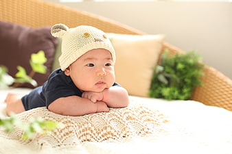 Adorable baby wearing a knitted bear hat lying on a soft blanket