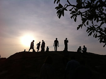 Silhouetted Group Of People On Hilltop At Sunset