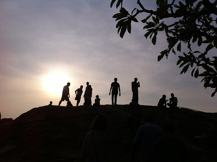 Silhouetted Group Of People On Hilltop At Sunset