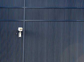 White Security Camera on Blue Corrugated Metal Wall