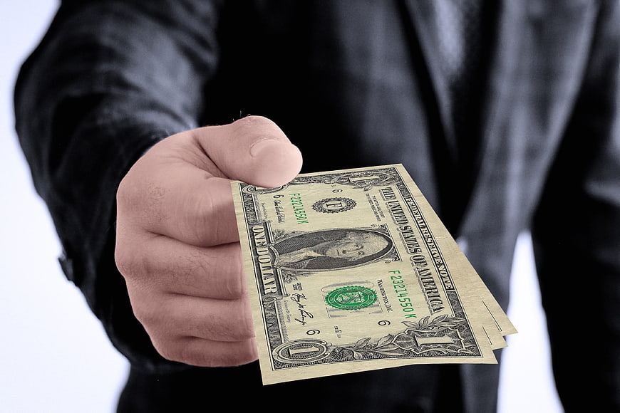 Hand holding one dollar bill in business suit
