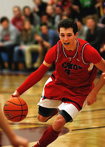 Teenage basketball player dribbling ball in red uniform during indoor game