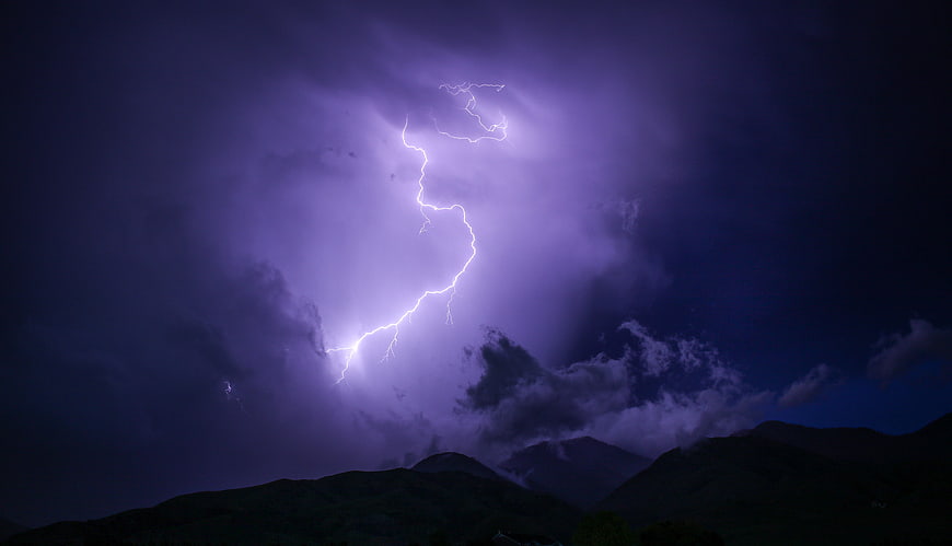 Dramatic Night Lightning Strike Over Dark Mountain Silhouettes