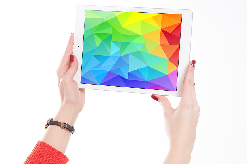 Hands holding white tablet with colorful geometric screen