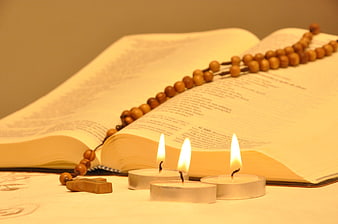 Open Bible with Wooden Rosary and Three Lit Candles