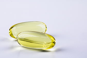 Two yellow softgel capsules on a white background