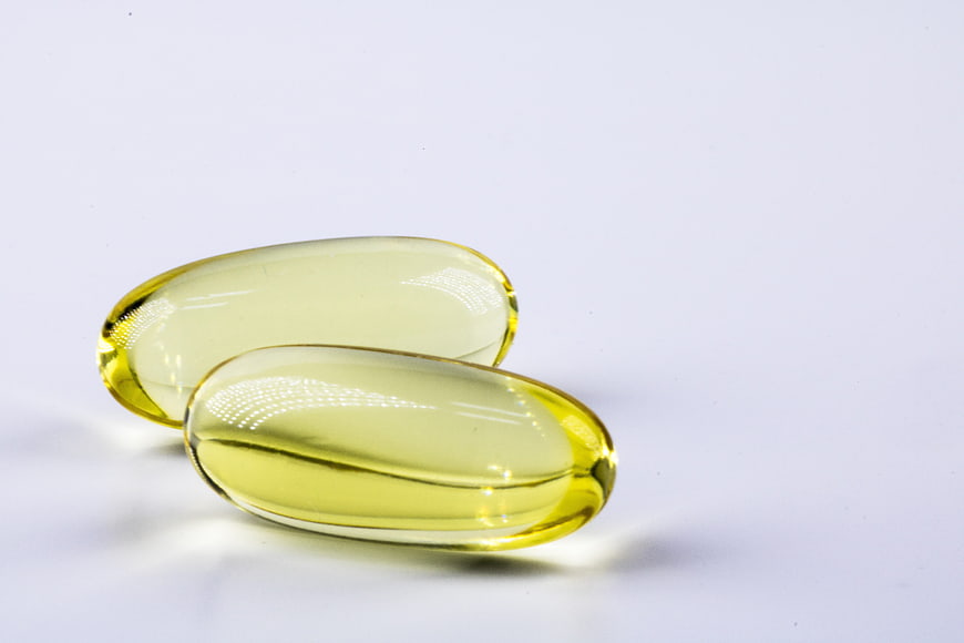 Two yellow softgel capsules on a white background