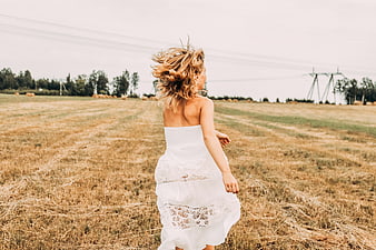 Woman in White Dress Running Through Golden Field
