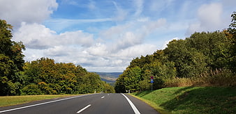 Empty asphalt road winding through green forest landscape