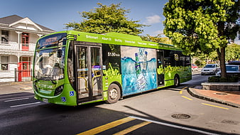 Green City Bus with Advertisement on Urban Street