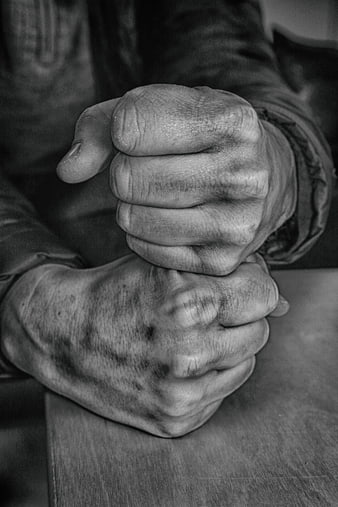 Close-up of weathered hands clasped in black and white