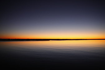 Serene Sunset Over Calm Ocean Water with Orange Sky