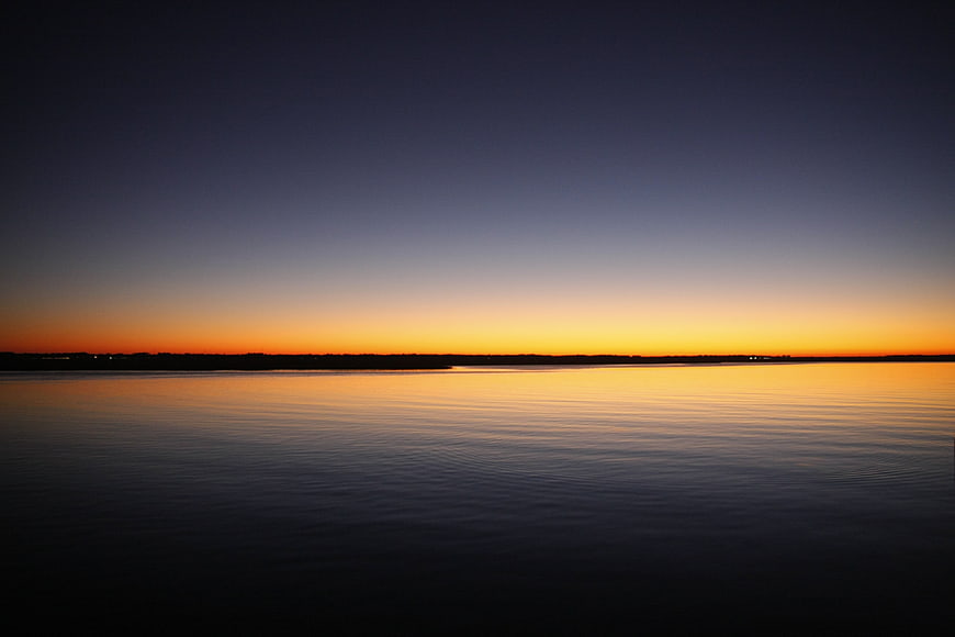 Serene Sunset Over Calm Ocean Water with Orange Sky