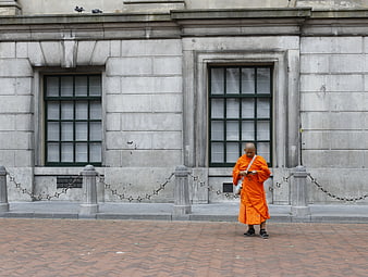 Buddhist Monk in Orange Robes Walking on City Street