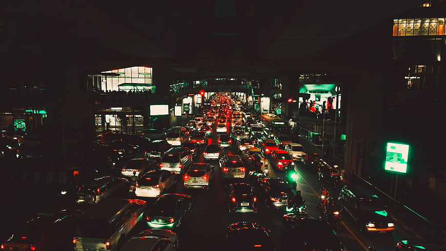 Night traffic jam under city overpass with neon lights