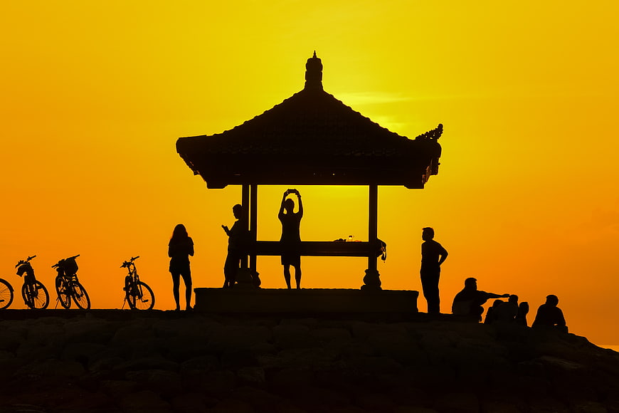 Silhouette of People and Bicycles at Temple Pavilion Sunset