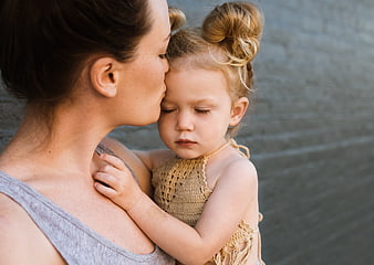 Mother kissing daughter's forehead in tender outdoor portrait