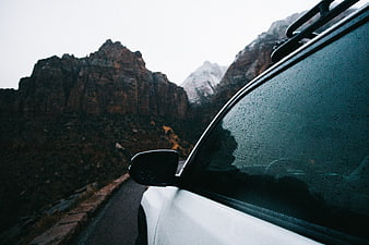 White SUV on Mountain Road with Raindrops